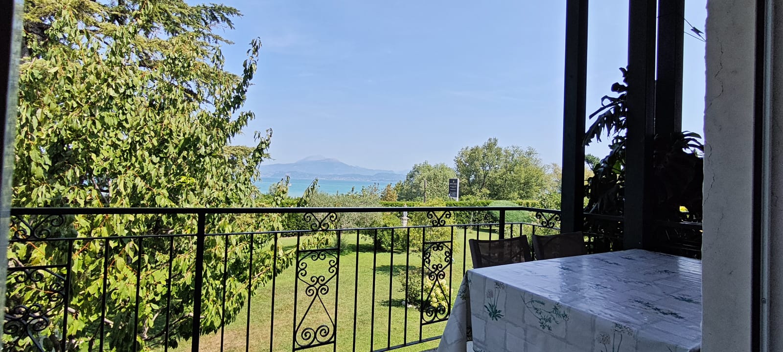 Appartamento 3.Arancio — terrazza con tavolo e ringhiera in ferro battuto, vista sul giardino e sul Lago di Garda