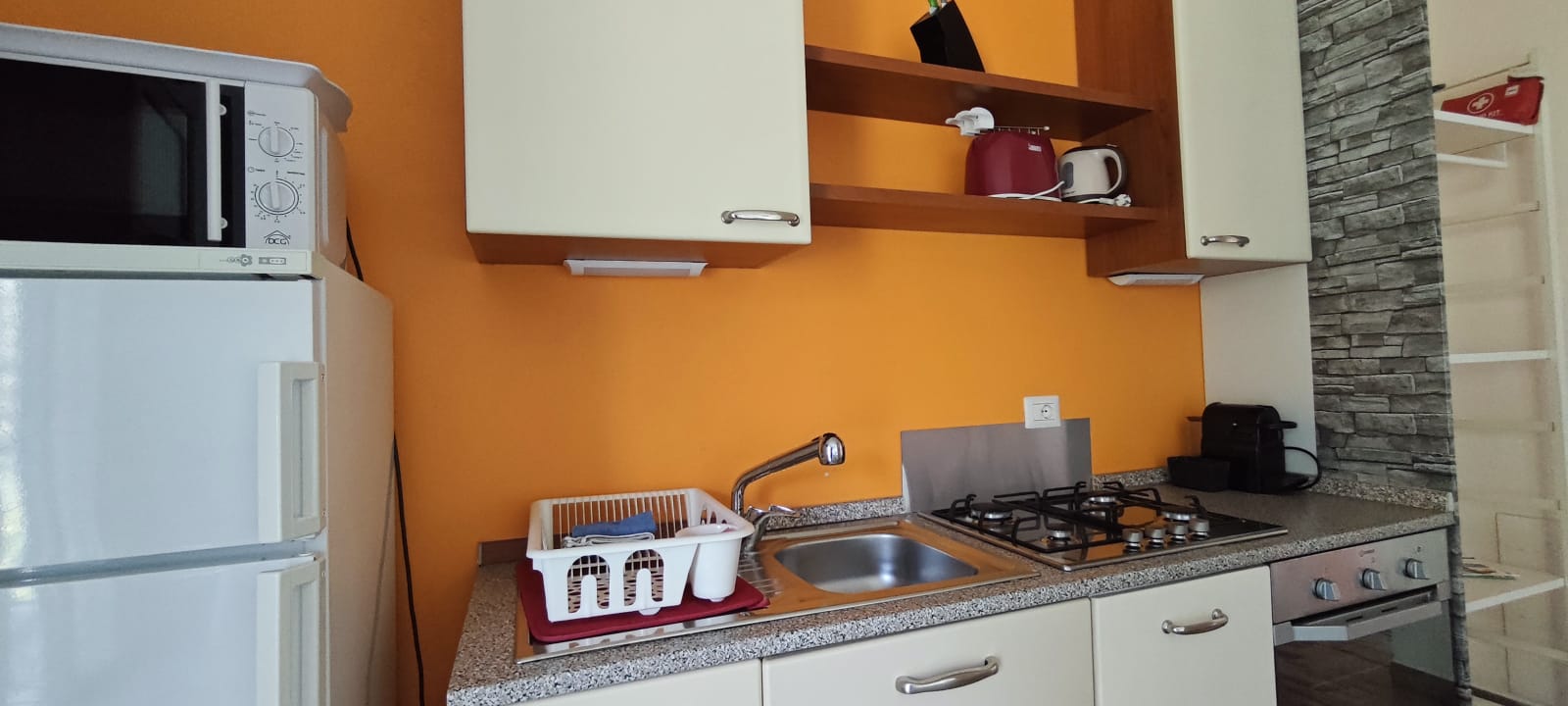 Apartment 3.Arancio — equipped kitchen with orange wall