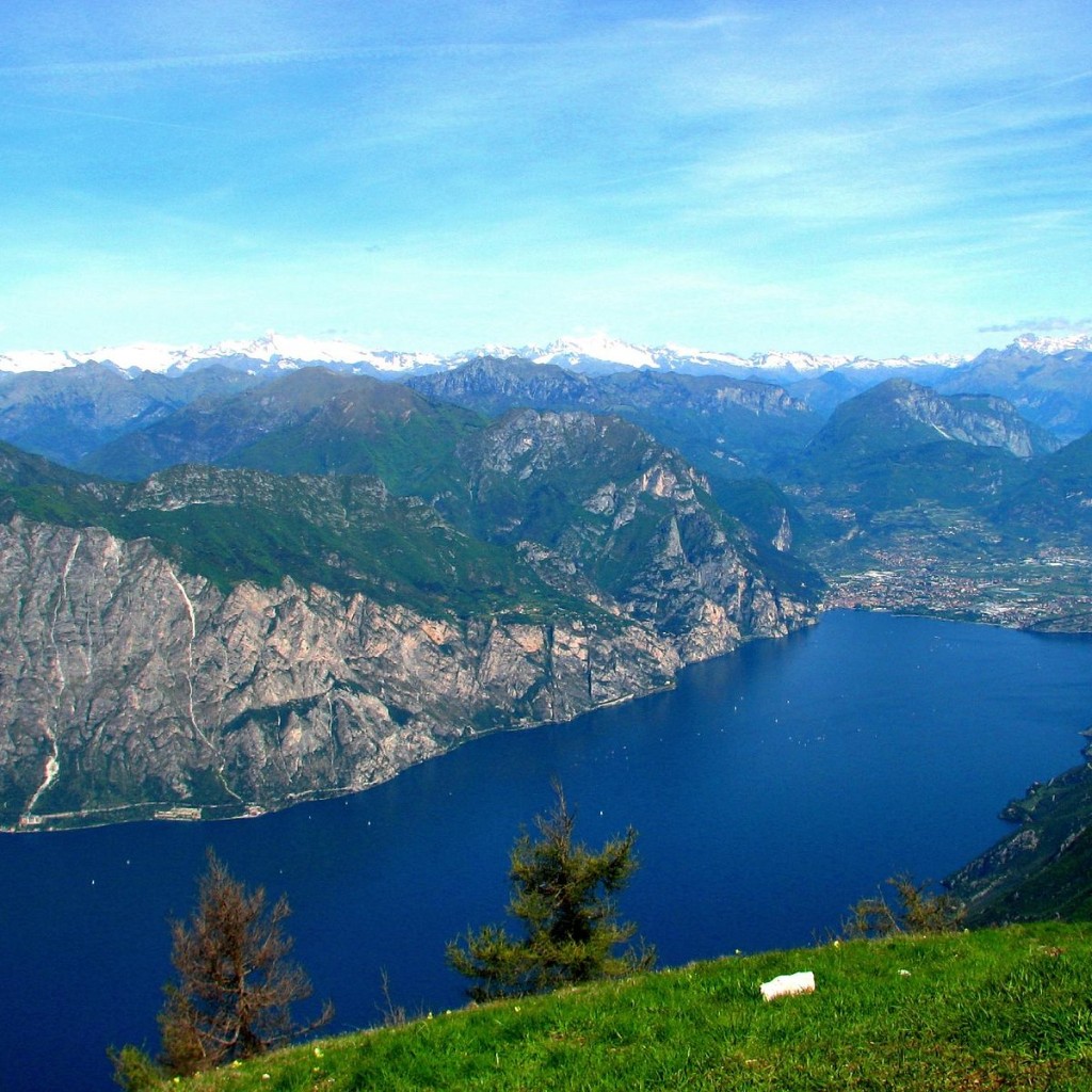 View of Lake Garda from the top of Monte Baldo, with rocky walls and snow-capped peaks