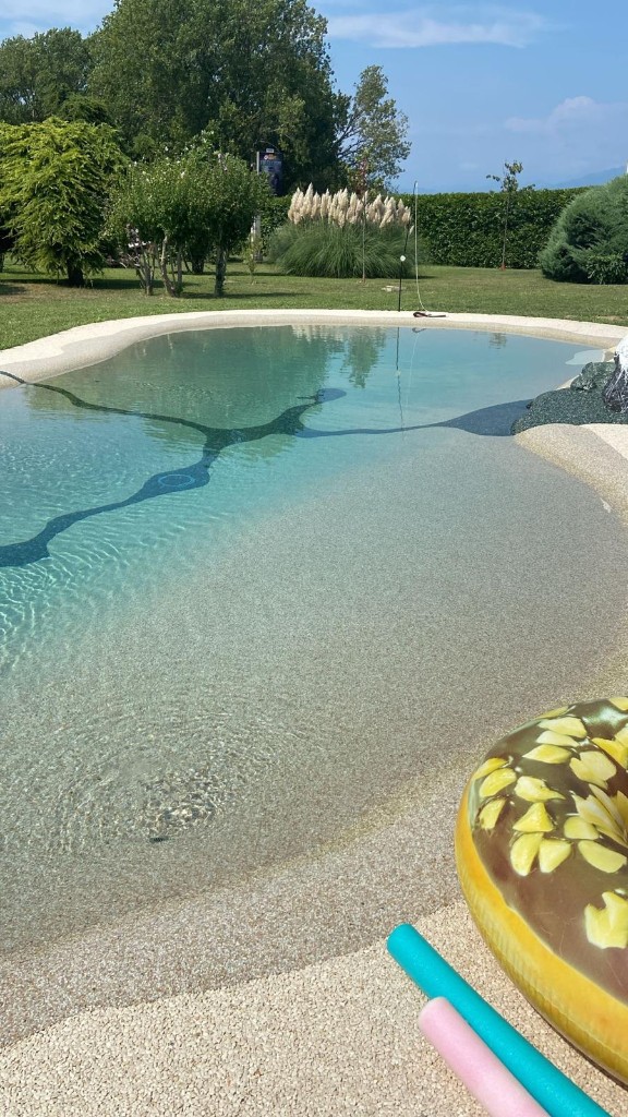 Acqua turchese e ingresso a spiaggia della piscina naturale di GioiaSulGarda