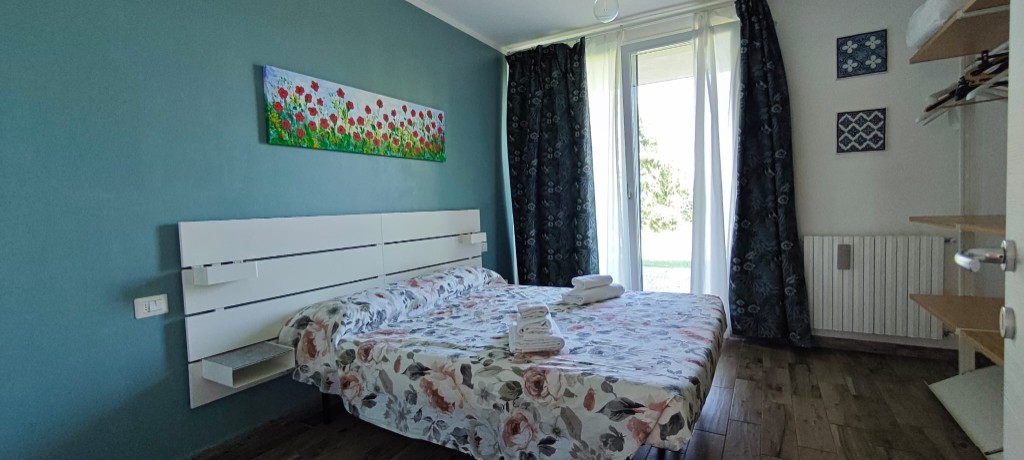 Apartament 2.Rosso — sypialnia z niebieską ścianą i widokiem na ogród