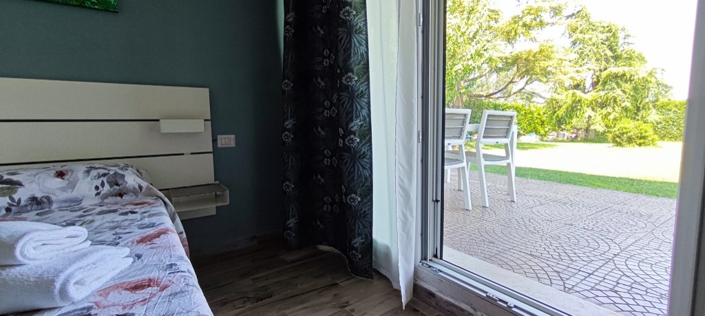 Apartament 2.Rosso — widok z sypialni na patio i ogród