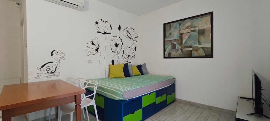 Apartament 1.Verde — salon z sofą z funkcją spania, stołem i Smart TV