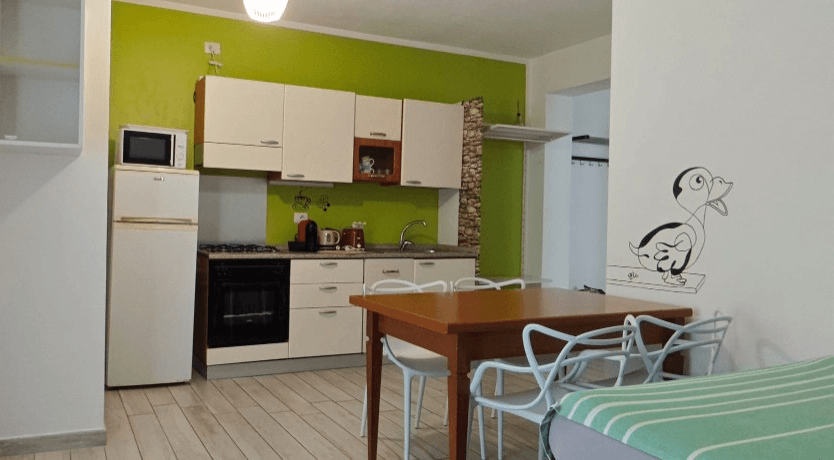 Apartament 1.Verde — wyposażona kuchnia z zieloną ścianą i jadalnią